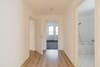 Innenansicht Flur mit Laminatboden Blick ins geflieste Bad mit Badewanne und ins Zimmer mit Teppichboden und Fenster