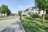 Straßenansicht eines viergeschossigen Mehrfamilienhauses mit weißer Putzfassade, Mansarddach, Vorgarten