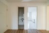 Innenflur einer Wohnung mit Laminatboden, Blick in Badezimmer mit Waschbecken und helles Zimmer mit Fliesenboden und Fenster