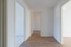 Innenansicht Flur einer leeren Wohnung mit hellem Holzfußboden und drei offenen Türen