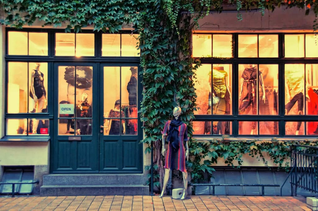 Frontalansicht eines Ladengeschäfts mit großen Schaufenstern und efeubewachsener Fassade