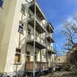 Mehrfamilienhaus Hofseite von unten mit drei übereinanderliegenden Stahlbalkonen und abgestellten Fahrrädern