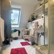 Innenperspektive Dachgeschossbadezimmer mit Dachfenster, weiße Fliesen, Glasdusche, WC, Waschbecken und roten Badteppichen
