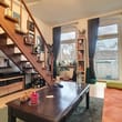 Innenansicht einer Altbauwohnung mit Wohnzimmer, offener Holztreppe, Balkontür und Couchtisch