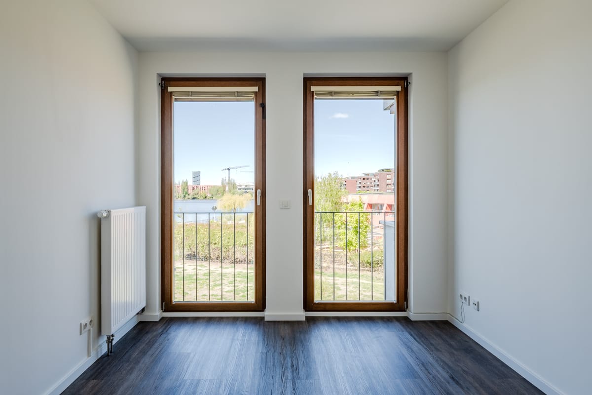 Helle Fensteransicht mit ruhigem Blick über Grünflächen und Wasserbezug