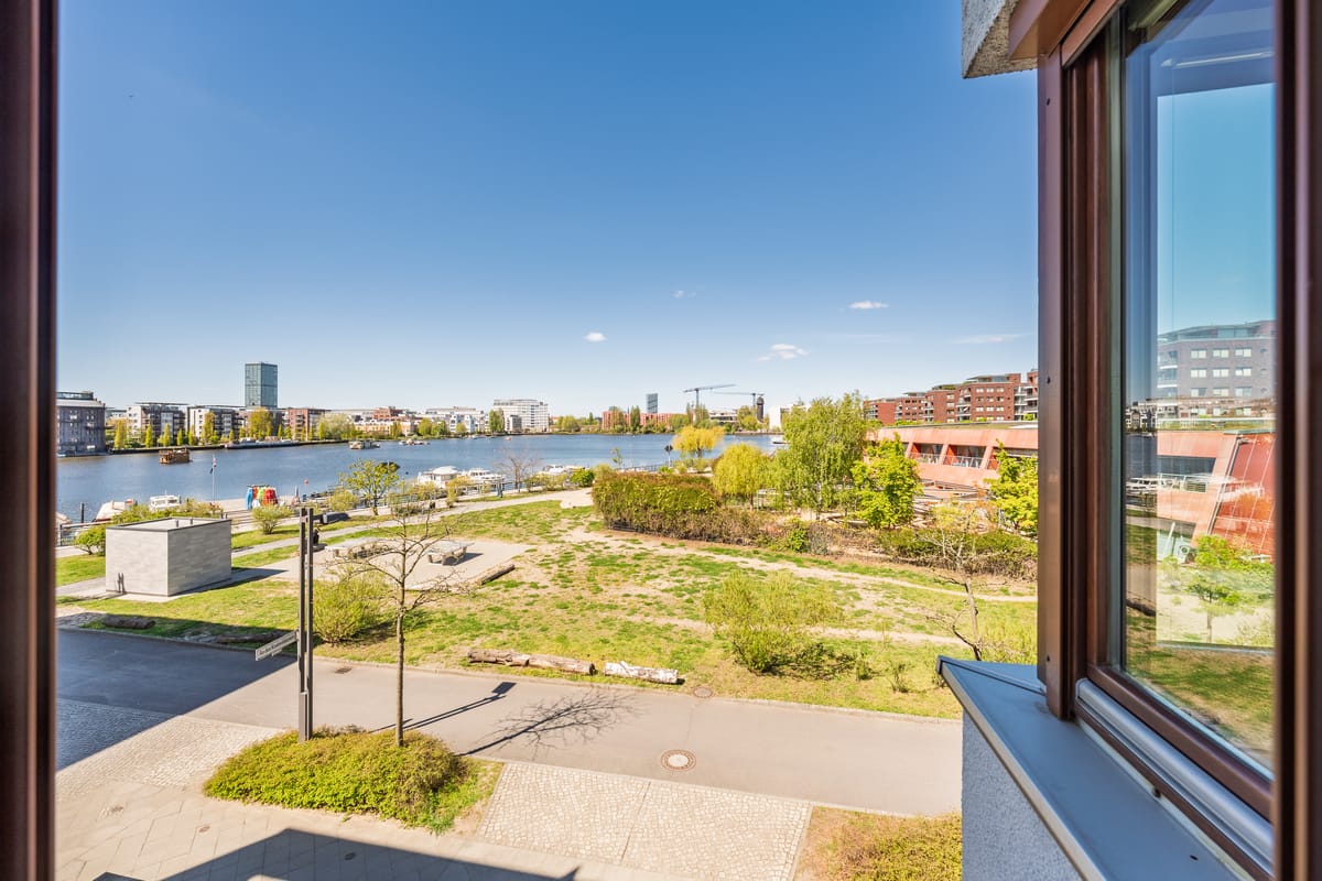 Blick über Grünflächen zur Uferpromenade und zum Wasser