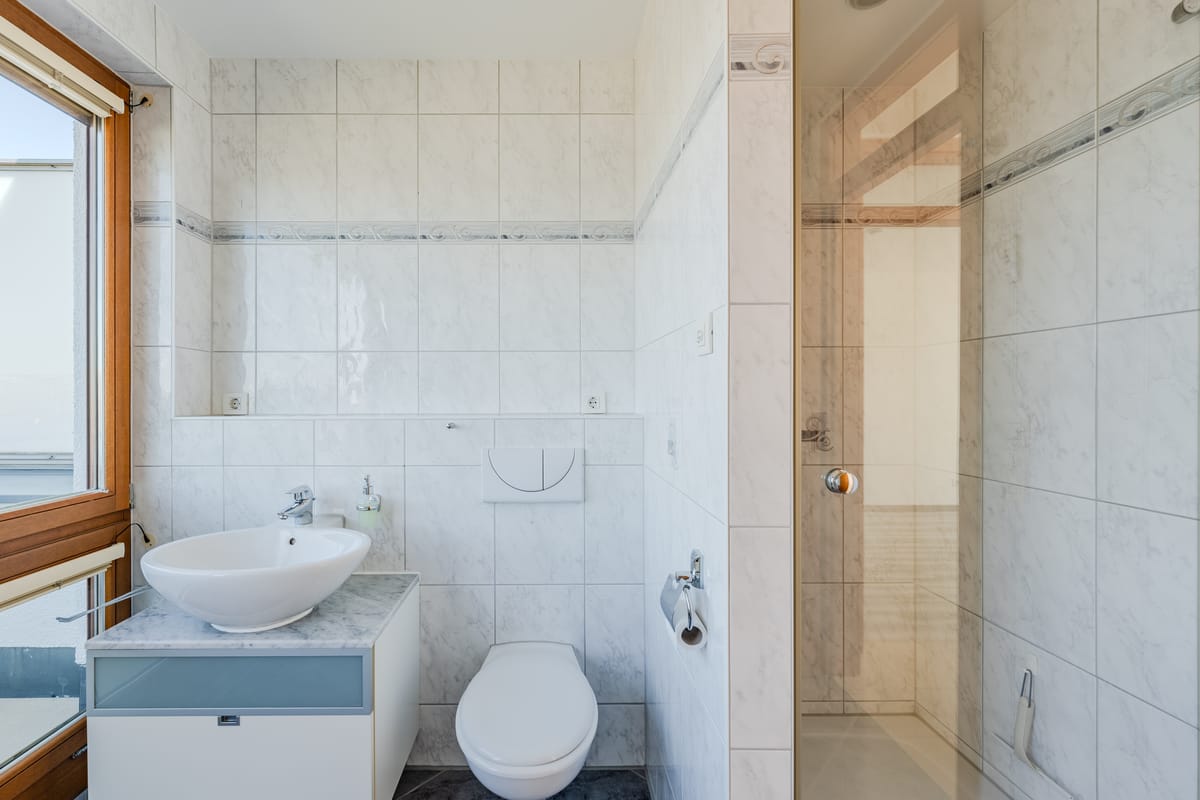 Detailansicht des Badezimmers mit Dusche und hellem Fliesenbild