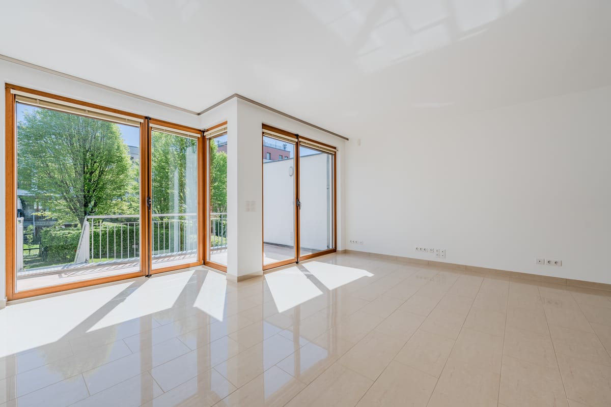 Weitläufiger Wohnbereich mit bodentiefen Fenstern und Blick ins Grüne