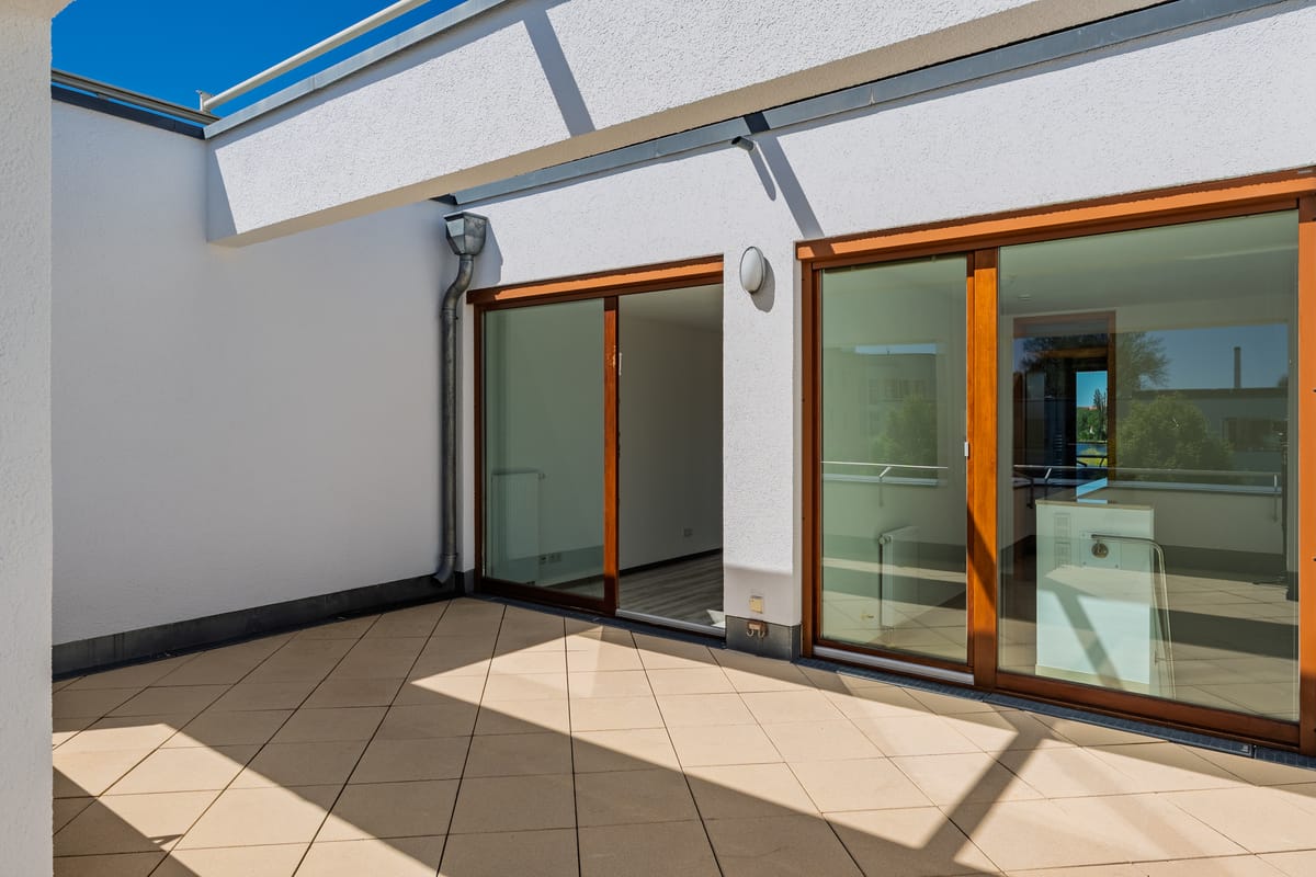 Dachterrasse mit großflächiger Verglasung und direktem Zugang zum Wohnbereich