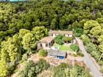 Luftaufnahme eines Landhauses mit Terrakotta-Dach, Carport, Terrasse und Garten umgeben von dichtem Kiefernwald