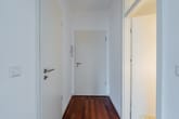 heller Wohnungsflur mit Echtholzparkett und weißen Innentüren in zentraler Perspektive