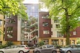 Mehrfamilienhaus frontalansicht mit zentraler Glasfassade Treppenhaus rote Metallfassade und begrünter Vorgarten