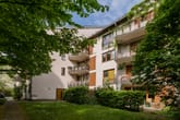 Mehrfamilienhaus mit drei Etagen Hofansicht weisse Putzfassade Holzläden Balkone und grüner Innenhof