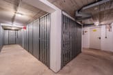 Kellerflur mit begehbarem Abstellbereich aus Metallgitter und weißer Technikraumtür