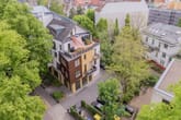 Vogelperspektive auf modernes mehrgeschossiges Stadthaus mit Dachterrasse und Balkonen umgeben von Bäumen