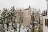 Innenhofansicht eines mehrstöckigen Wohnhauses mit verschneitem Gartenbereich Sitzbänken unbelaubten Bäumen und Balkon