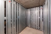 Blick in ein leerstehendes Kellerabteil mit grauen Metalltrennwänden und Betonboden