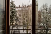 Ausblick vom Wohnungsbalkon auf verschneiten Innenhof mit Laubbäumen und mehrgeschossigen Wohnhäusern