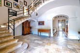 Geräumiger Hausflur mit geschwungener Steintreppe und Bogenöffnung zum Wohnzimmer auf Natursteinboden