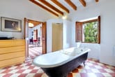 Innenaufnahme eines loftähnlichen Badezimmers mit freistehender Badewanne sichtbaren Holzbalken und Kachelboden