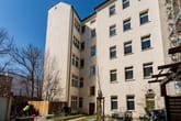 Hofansicht eines fünfgeschossigen Mehrfamilienhauses in Putzoptik mit Fenstern, Fahrrädern und Baugerüst