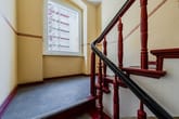 Innenansicht Treppenhaus mit rotem Holzgeländer und Fenster mit Blick auf Gerüst