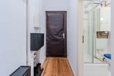 Innenflur einer Altbauwohnung mit brauner Eingangstür, offener Duschkabine, WC und sichtbarer Heiztherme