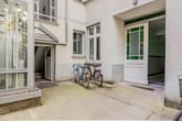 Innenhof eines Mehrfamilienhauses mit gläsernem Aufzug grünverglaster Eingangstür und zwei abgestellten Fahrrädern