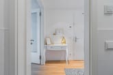 Blick in hellen Wohnungsflur mit weißem Konsolentisch, goldener Lampe und Parkettboden