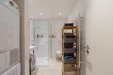 Innenaufnahme Apartment-Bad mit ebenerdiger Dusche, Hänge-WC, Handtuchheizkörper und Korbregal