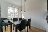 Moderner Essbereich in Neubauwohnung aus Eckperspektive mit dunklem Holztisch und Polsterstühlen