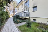 Cam balkonlu, taş döşeli yolu ve herdem yeşil çitli parlak apartmanın yan görünüşü