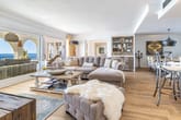 Offener Wohn- und Essbereich einer Ferienwohnung mit Ecksofa Holzboden und Meerblickbalkon