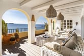Terrassenblick auf das Meer mit weißen Rundbögen, Rattanmöbeln und Kakteendekor