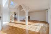 Offener Dachgeschoss-Wohnraum mit weißen Holzbalken, Parkettboden, Dachfenster und gläserner Schiebetür