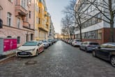 Straßenansicht von Altbauten mit bunten Putzfassaden und Balkonen an Kopfsteinpflasterstraße mit parkenden Autos