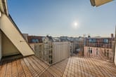 Dachterrasse mit Holzbelag und Metallgeländer frontal mit Blick über umliegende Stadtdächer