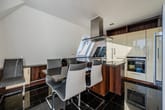 Innenaufnahme einer Dachgeschosswohnung mit offener Küche und Kochinsel aus Granit unter schrägen Dachfenstern