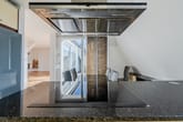 Blick von moderner Kochinsel auf offenen Penthouse-Wohnbereich mit Induktionskochfeld Dunstabzug und Terrassentür