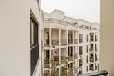 Blick von Balkon auf moderne mehrstöckige Wohnanlage mit weißen Fassaden und Reihenbalkonen