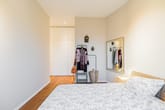 Schlafzimmer in moderner Wohnung aus Blickrichtung zur Wand mit Einbauschrank Rattankopfteil und Spiegel