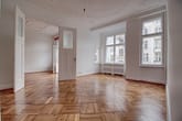 Leerstehendes Altbauapartment mit Fischgrätparkett, Stuckdecke, geöffneter Doppeltür und hohen Fensterfronten