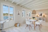 Innenansicht eines hellen Meerblick Apartments Essbereich mit Holzbalkendecke Korbleuchte und Doppelflügeltür zum Balkon