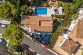 Vogelperspektive auf mediterranes Einfamilienhaus mit Ziegeldach, Pool, Sonnenschirmen und gepflegtem Garten