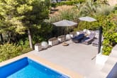 Vogelflugperspektive auf Poolterrasse einer Villa mit Liegen, Sonnenschirmen und mediterraner Bepflanzung