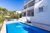 Weiß verputzte Villa mit Pool und Sonnenterrasse aus seitlicher Perspektive mit überdachtem Balkon