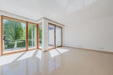 Weitläufiger Wohnbereich mit bodentiefen Fenstern und Blick ins Grüne