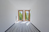 Schlafzimmer mit großer Fensterfront und grünem Ausblick