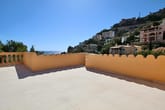 Dachterrasse mit geschwungener gelber Brüstung und Meerblick auf Hangvillen im Hintergrund