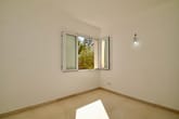 Innenansicht leeres Zimmer mit Eckfenster, weißem Fliesenboden und nackter Lampenfassung an Wand